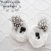 White and black flower shoe clips filled with Swarovski crystals, dusted with spotted feathers.