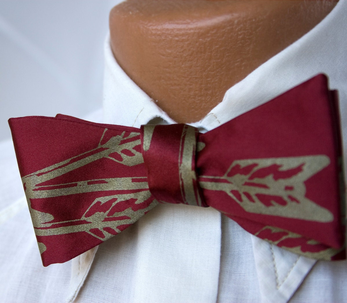 Burgundy Arrows bow tie, freestyle. Silkscreened necktie, antique brass print. "Quiver."