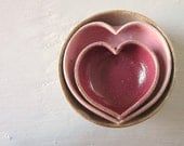 red and pink pottery hearts nested with a miniature rustic white bowl