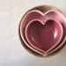 red and pink pottery hearts nested with a miniature rustic white bowl