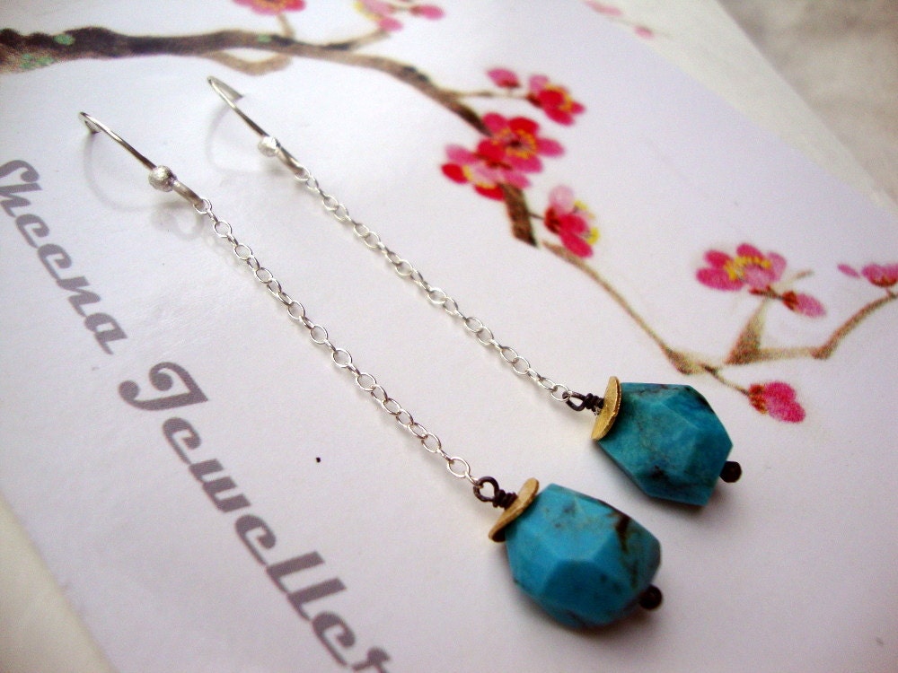 Long geometric turquoise stone earrings on silver chain.