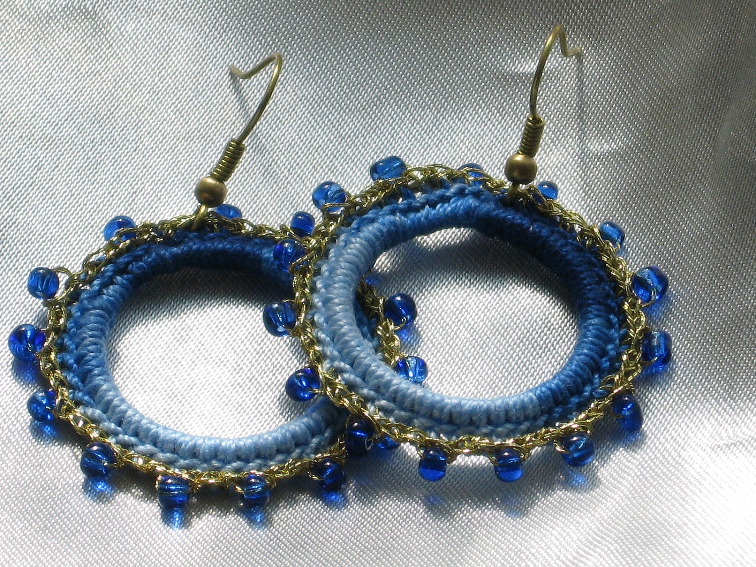Crocheted hoop earrings with blue shades cotton yarn and gold thread with blue glass beads