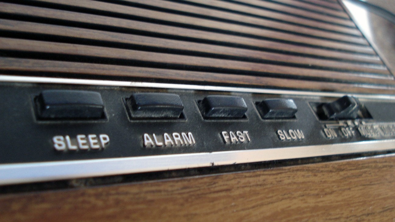 Vintage 1970s General Electric alarm clock with red digital numbers and woodgrain exterior
