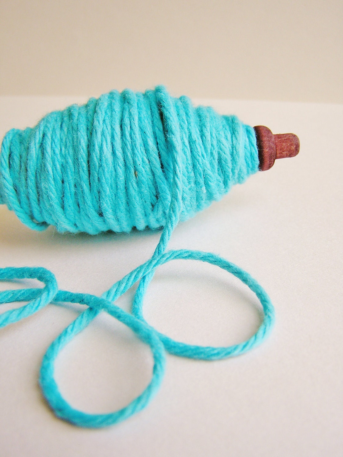 Turquoise thick cotton twine on a chocolate spindle