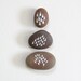 handpainted beach pebbles with droplet designs // white on brown and rust // by natasha newton