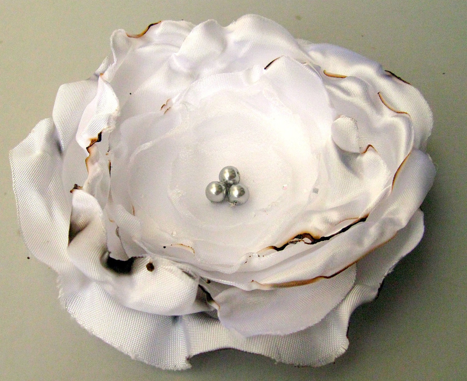 Handmade fabric flower in antiqued white satin.