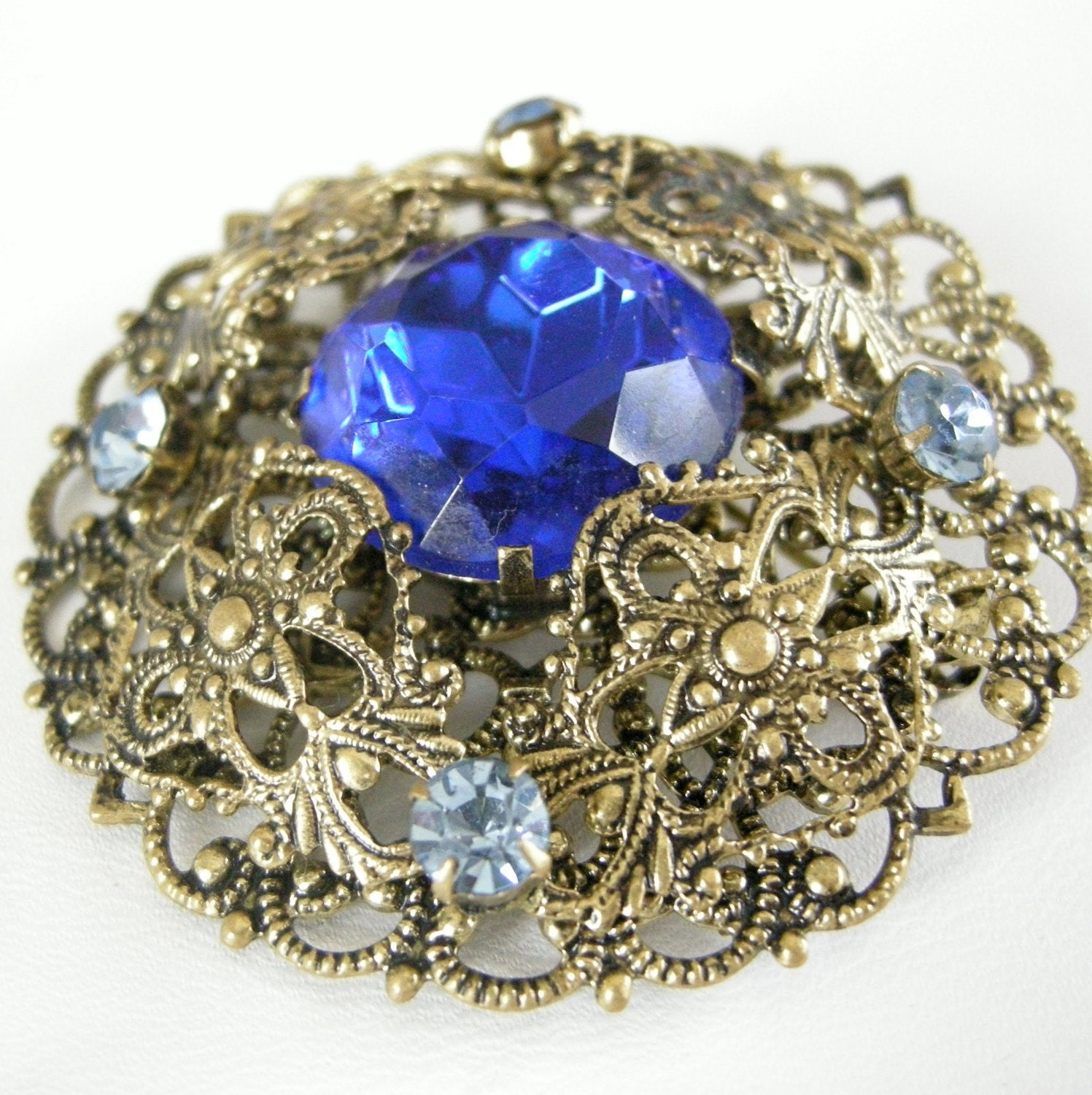 Vintage antiqued brass filigree dome brooch with sapphire blue glass, rhinestones