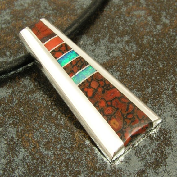 Silver pendant inlaid with dinosaur bone, red coral and Australian opal.