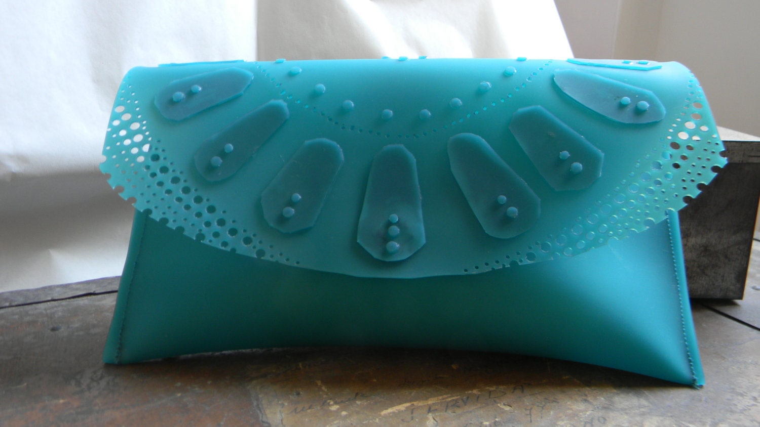 Turquoise lace pattern clutch bag in rubber.
