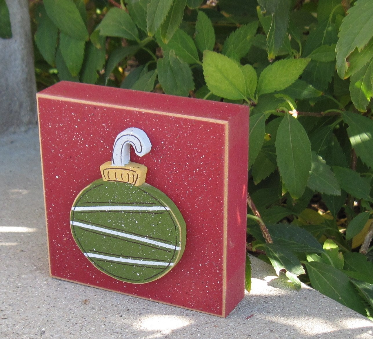 Green round ornament on red block for Christmas, Noel, shelf, desk, office, mantle and home decor