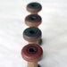 Four Small Wooden Bobbins with Ratcheted Tops and Colored Bottoms