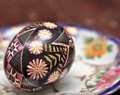 Ring-Around-The-Rosy Pysanky Egg: A Garland of Pink, Yellow and White Blooms Encircles Traditional Scarves on Black Background