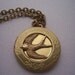 The  Hunger Games real not real hand stamped Peeta's  locket with mockingjay
