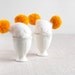 White egg warmers with funny yellow poms