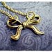 Tiny Golden Bow Charm Necklace in Antique Gold Pewter with a Delicate 18 Inch Gold Plated Cable Chain