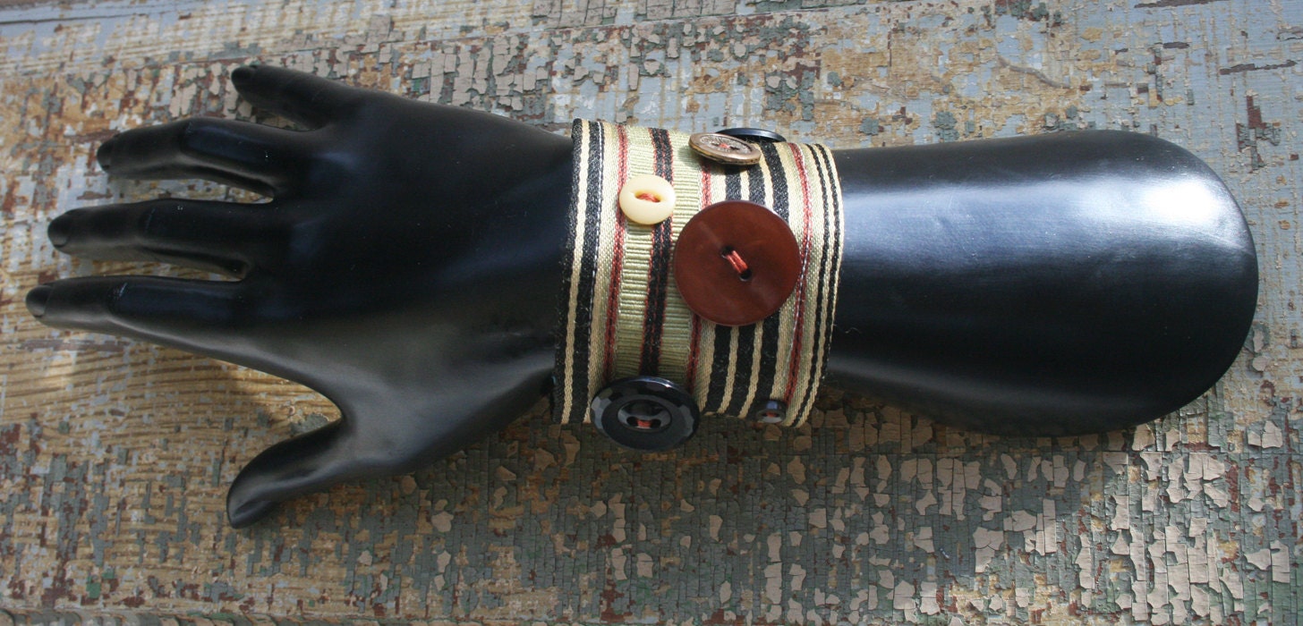 Gold, black, and red striped bracelet with brown and black vintage buttons