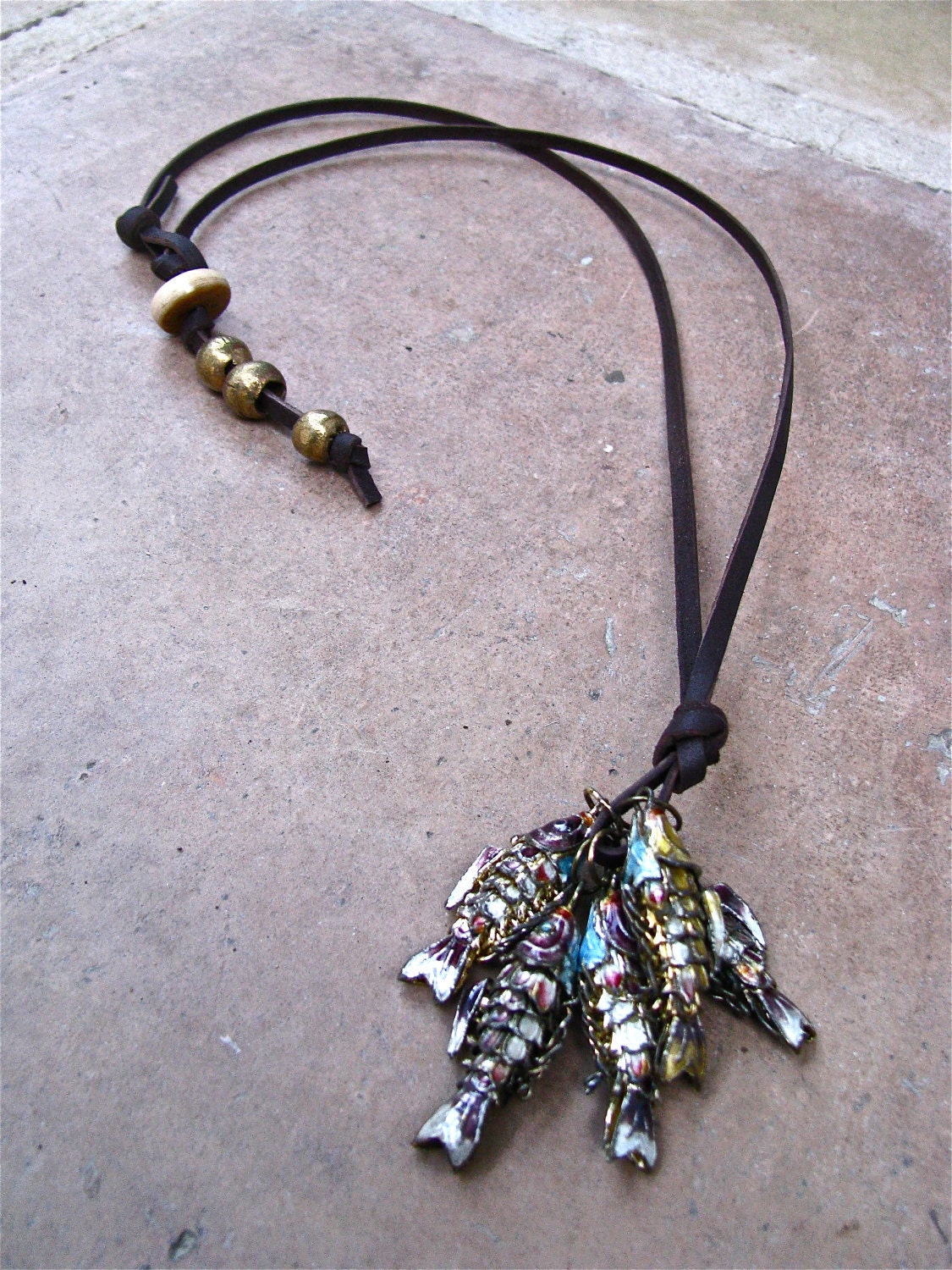 Fish On A Hook Necklace Made of Base Metal Colored Fish Strung on Brown Leather with a Self Closure of African and Bone Beads