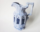 Unusual Embossed Blue Ceramic Pitcher with Bas Relief Figures