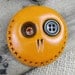 Happy orange mini skull brooch with a khaki green button in is eye