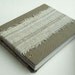 Torn fabric covered blank book in gray hues.