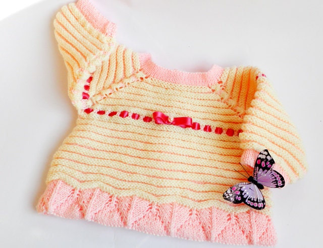 Hand knitted baby cardigan in soft colors, decorated with satin ribbon