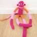Knee sock monkey plush doll with color blocked magenta, pink, and orange stripes
