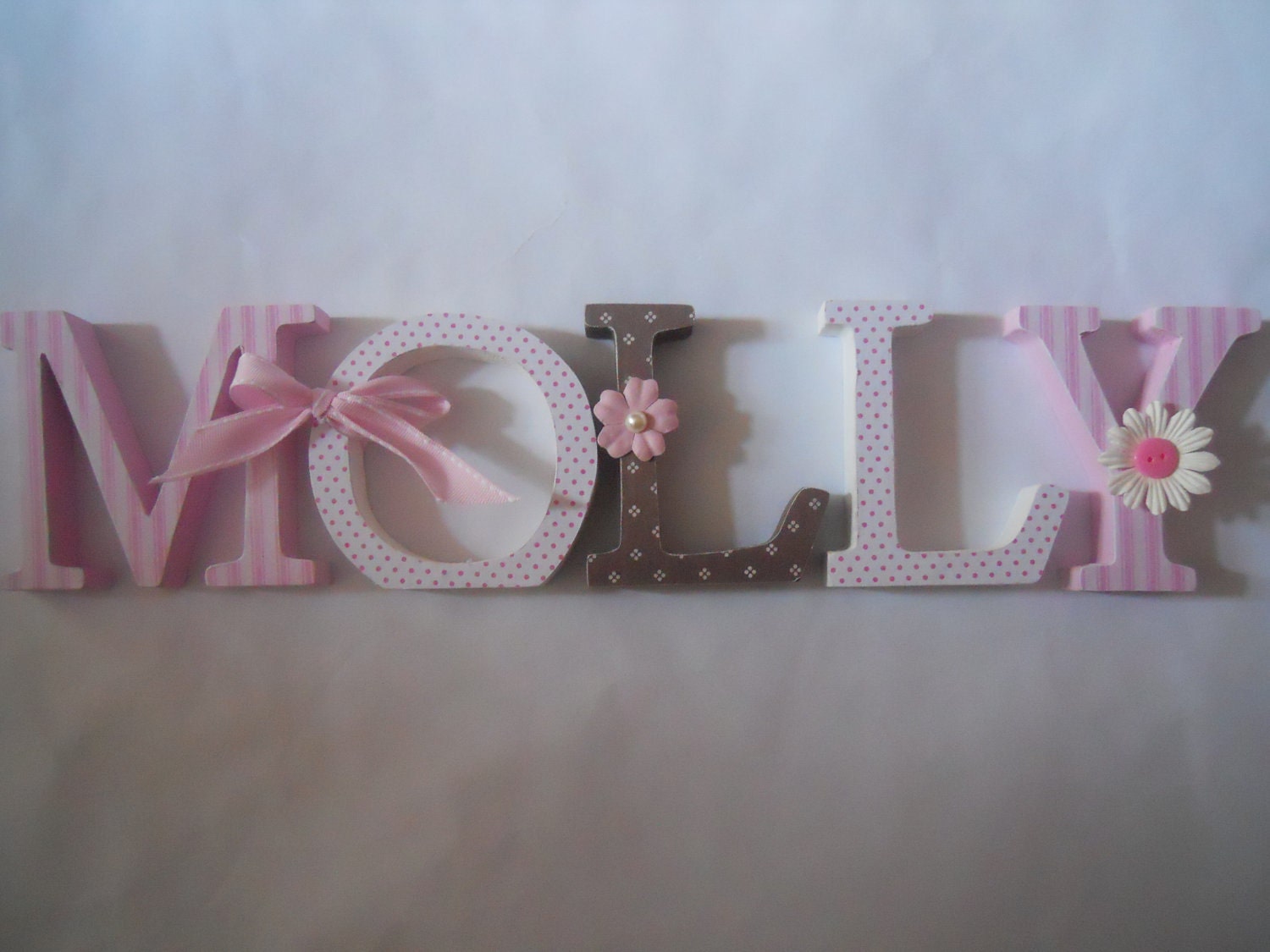 Wooden letters for nursery in pink, white and brown.