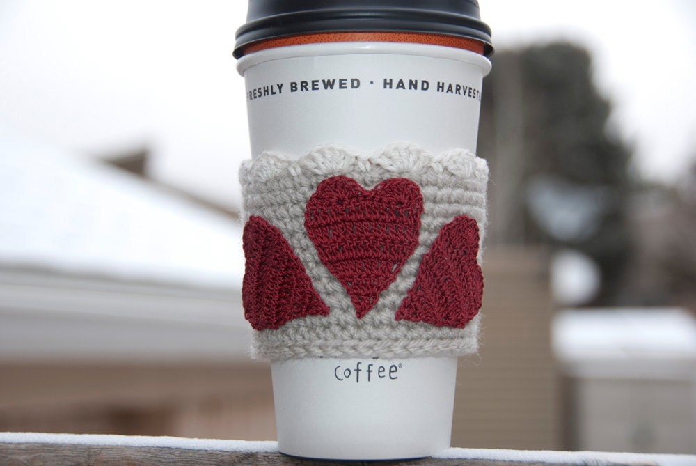 Hand crocheted coffee cosy cozy, three red be mine valentine gift hearts on a linen sleeve with a snow white lace trim
