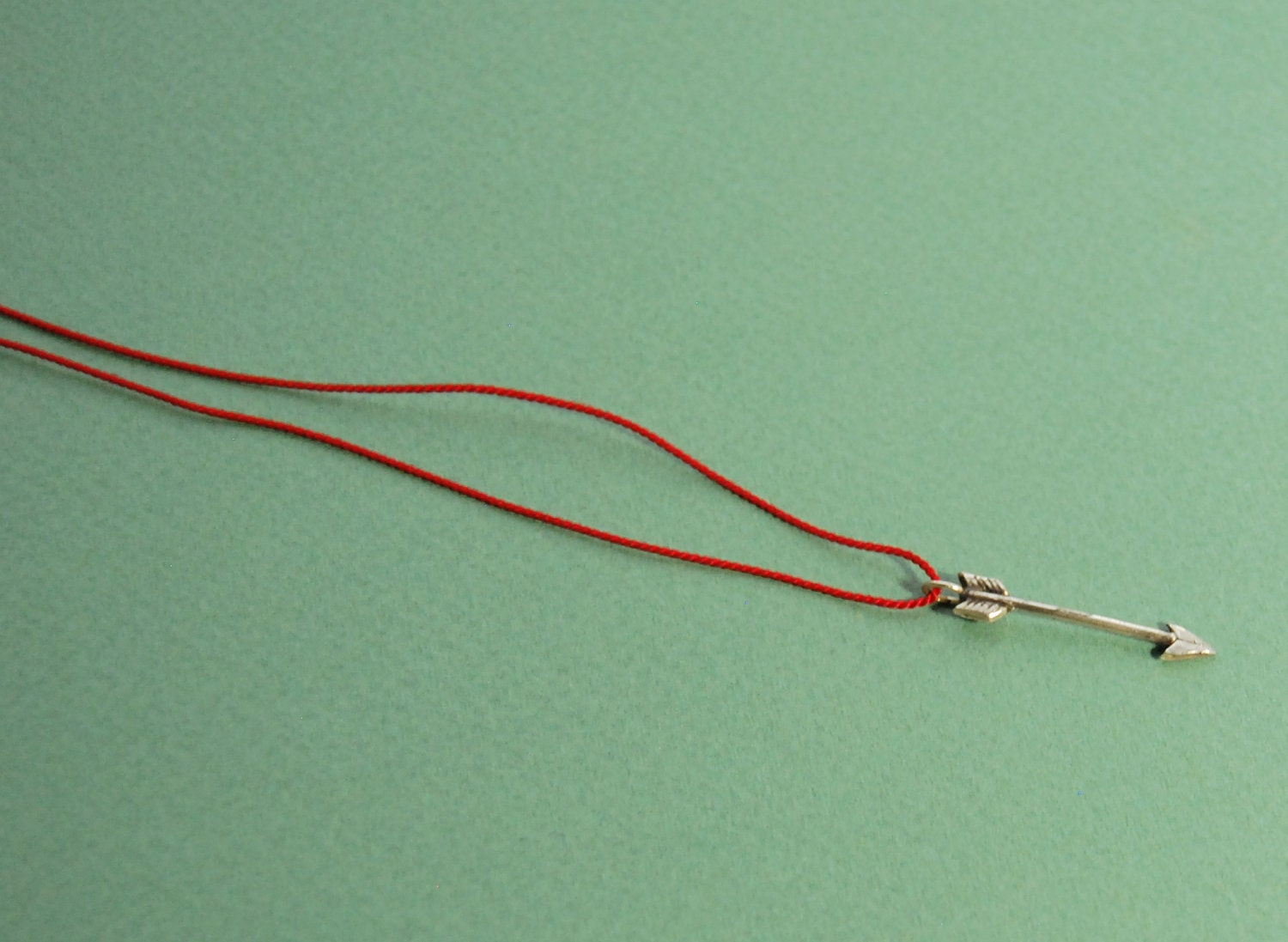 Silver arrow pendant on red silk cord