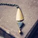 yoko. a gold and gray geometric triangle necklace.