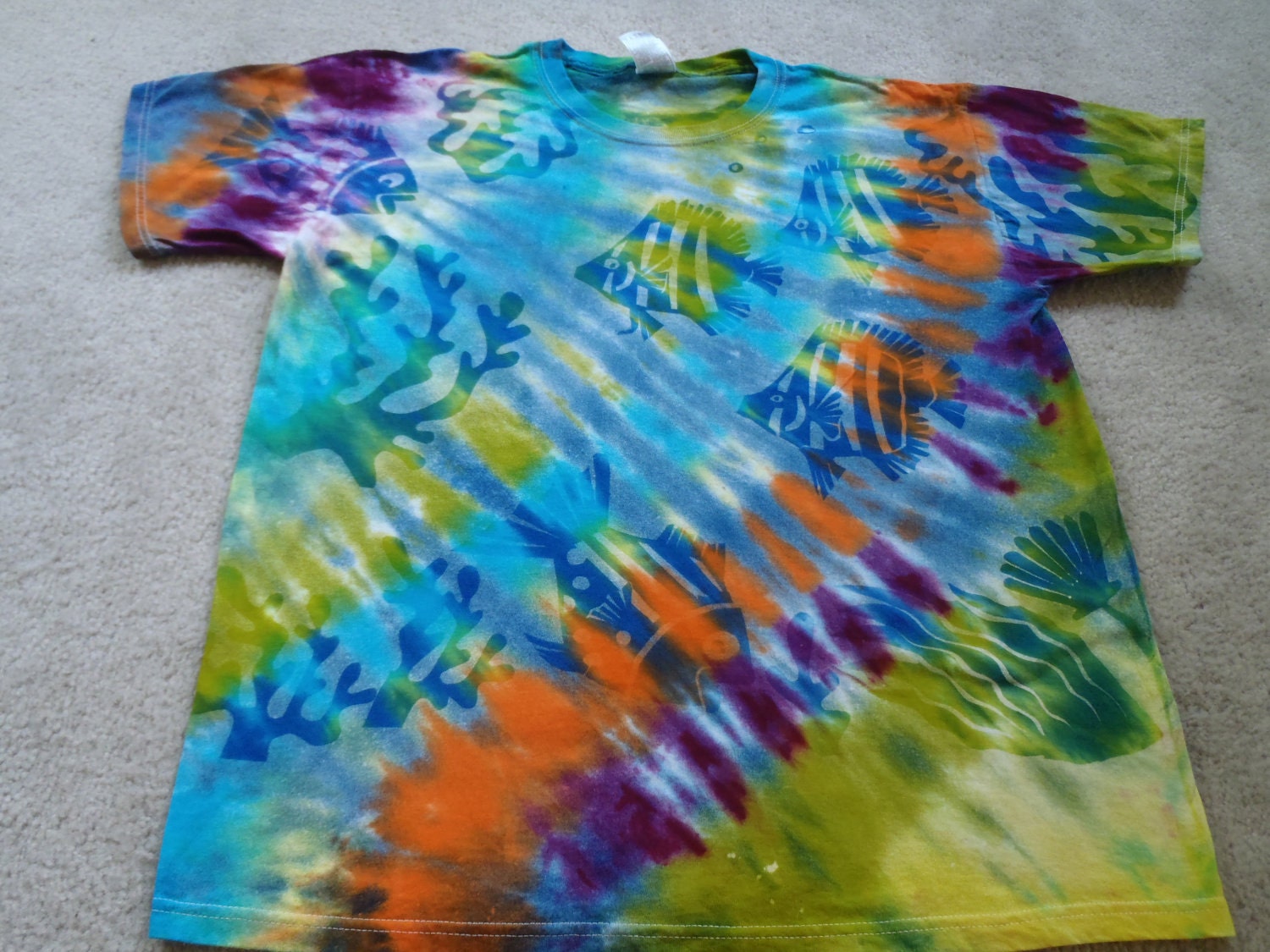 Tie dyed t-shirt and then discharge to create an ocean scene, vibrant colors, fish, turtles, and coral