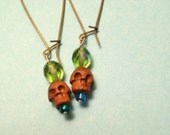 Wooden skull earrings with green and blue beads