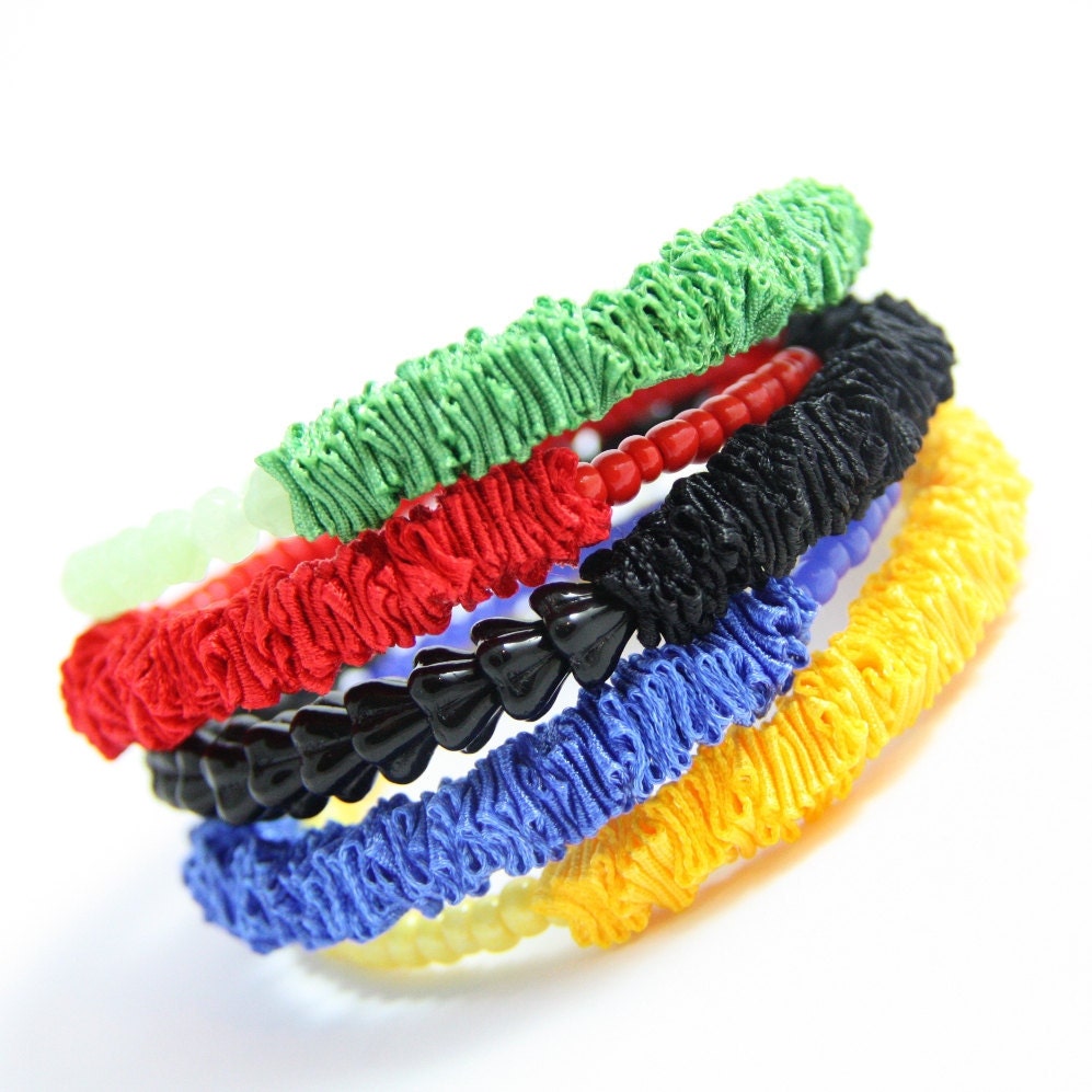 Stackable bracelets made of memory wire in the colors of the Olympic games symbol. Ribbon and beads in green, red, black, blue, yellow.