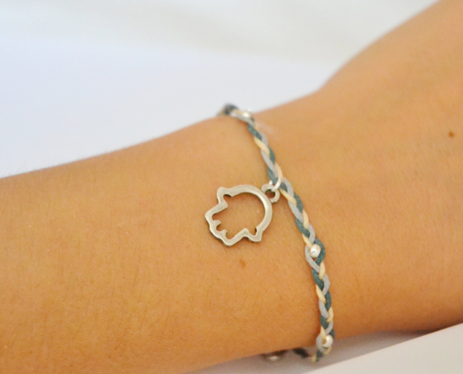 Braided Hamsa Bracelet- braided bracelet with a silver plated hamsa charm and 3 cords: gray, blue, beige. Decorated with silver plated beads