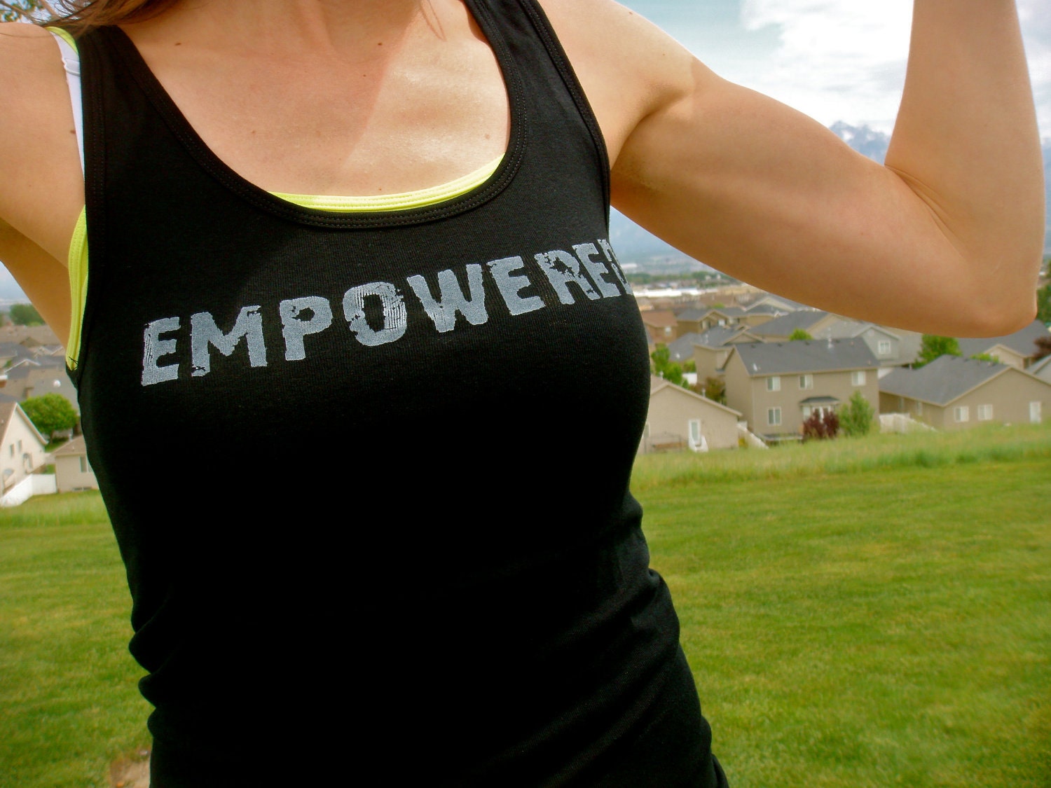 Empowered done in vintage looking silk screen on a black workout tank top with a tied up in knots back
