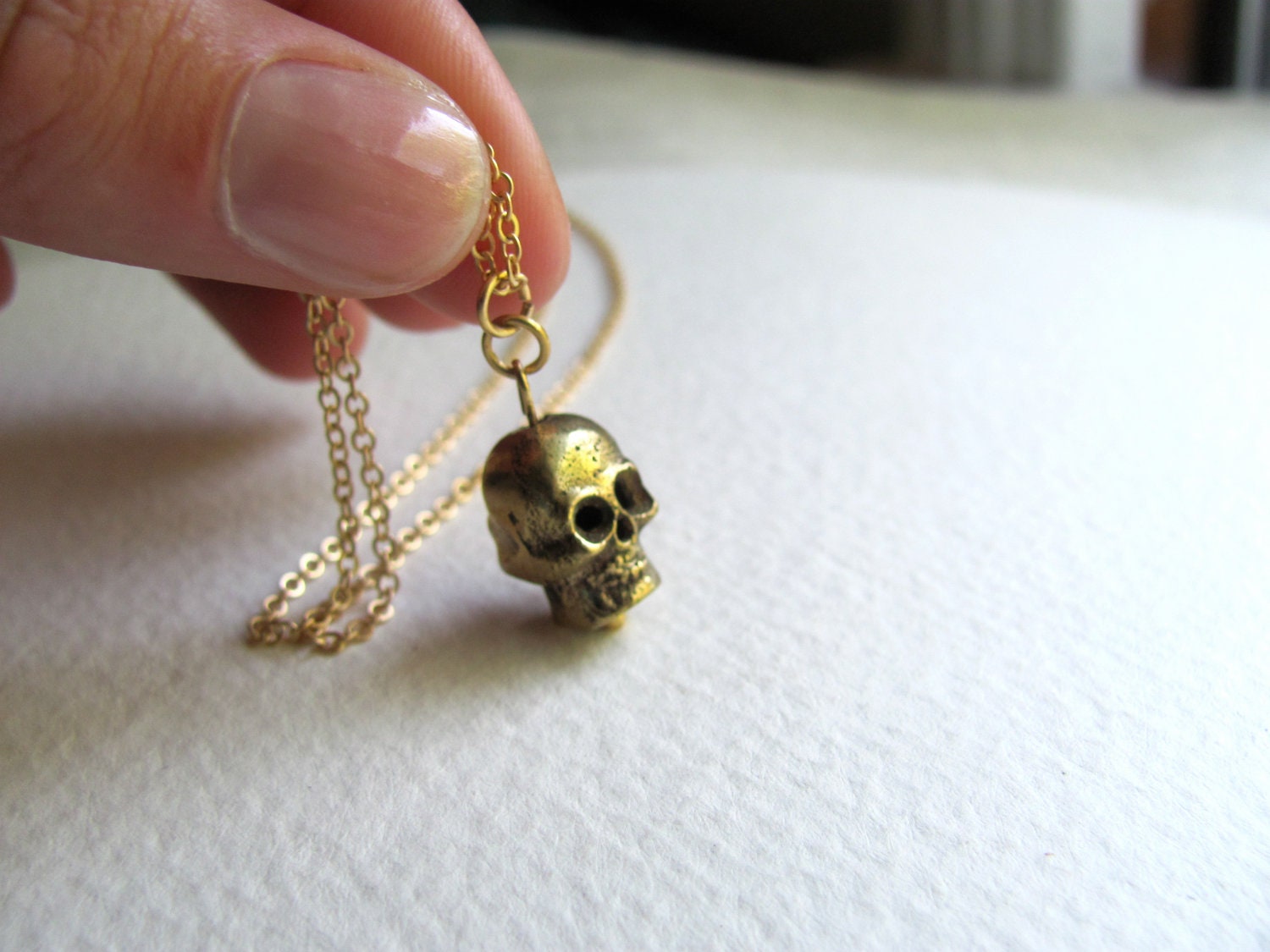 Gold skull charm necklace on delicate 14k gold plate chain, satin finish