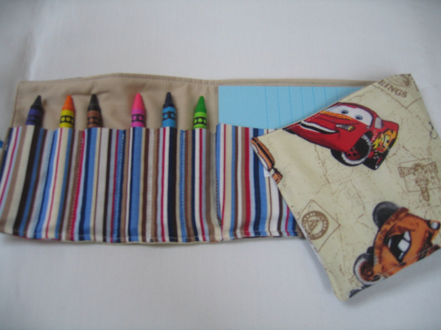 Tan Mater Crayon Tote in a colorful print complete with 12 crayons and a paper pad