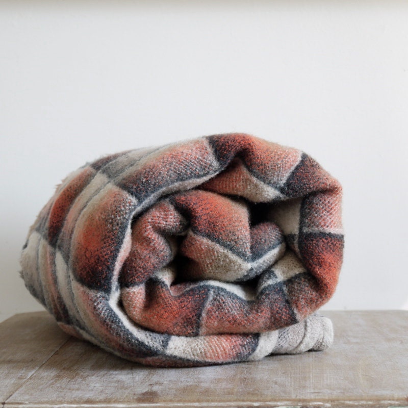 Vintage wool blanket in optical check square pattern in orange red grey gray and black.