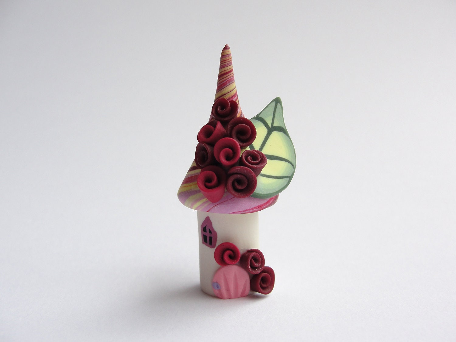 Miniature fairy house home made from polymer clay in yellow, pink and red