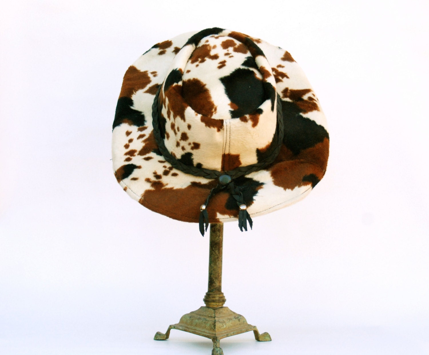 Western cowboy hat, faux cowhide print and leather braided strap.