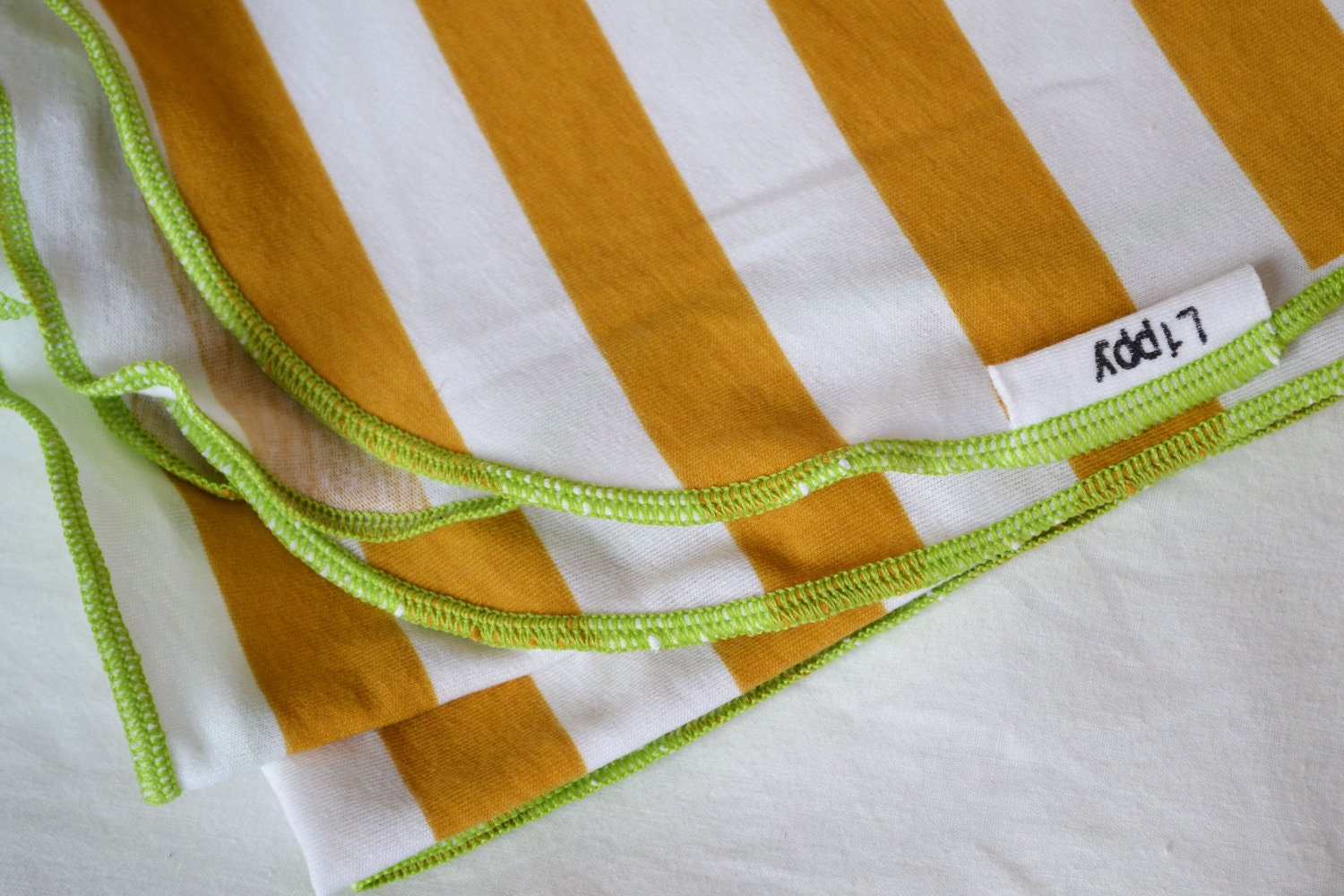 Baby swaddling blanket. Gender neutral- deep yellow and white with green edging.   Made by lippy brand.