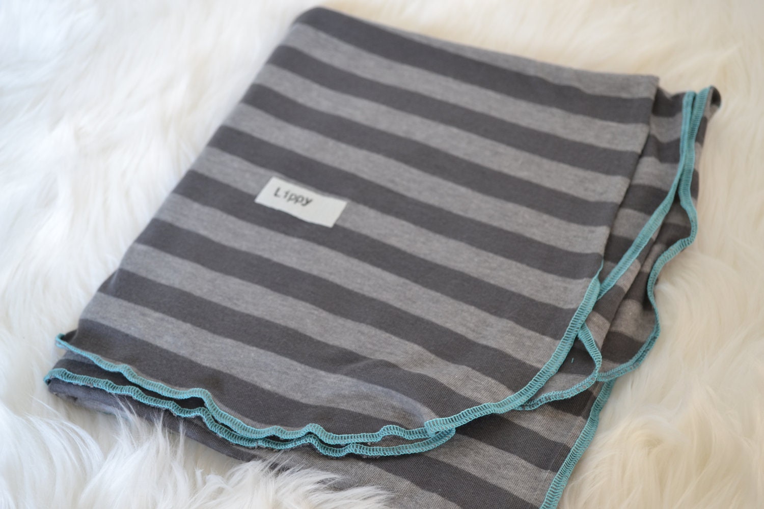 Swaddler baby blanket.  Size 31 by 40 inches.   Colors- gray and light gray with blue edging.   Made by lippy brand.