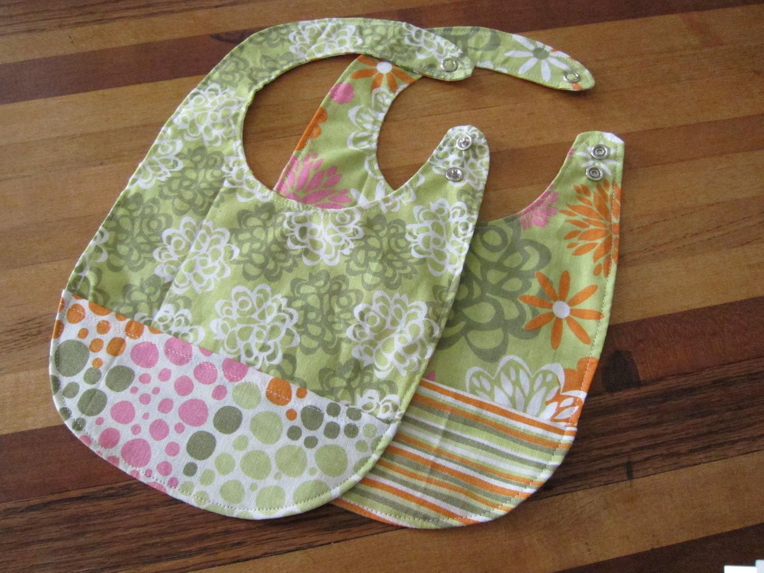 Set of 2 Reversible and Adjustible Bibs with Pockets in Green, Orange, and Pink Prints