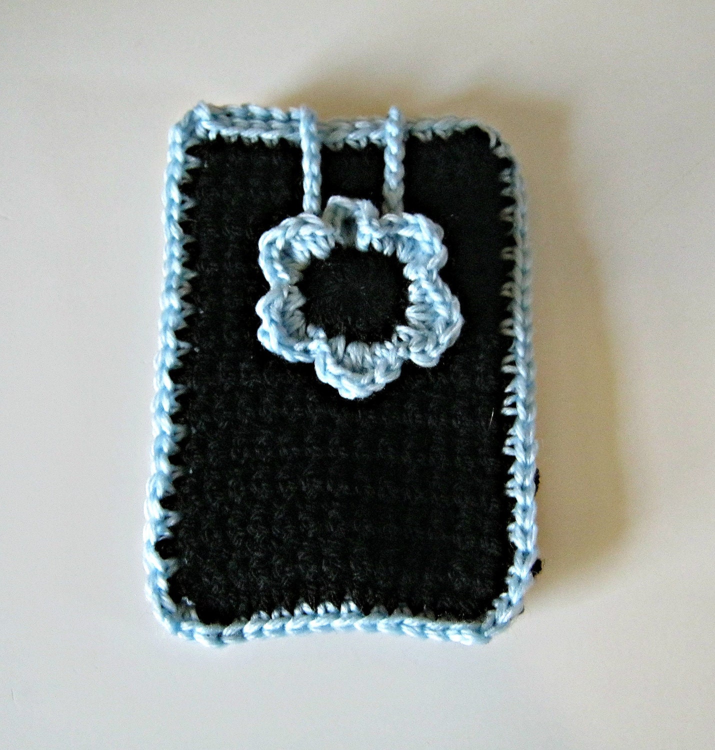 Crocheted phone cover in black with a pale blue flower and trim