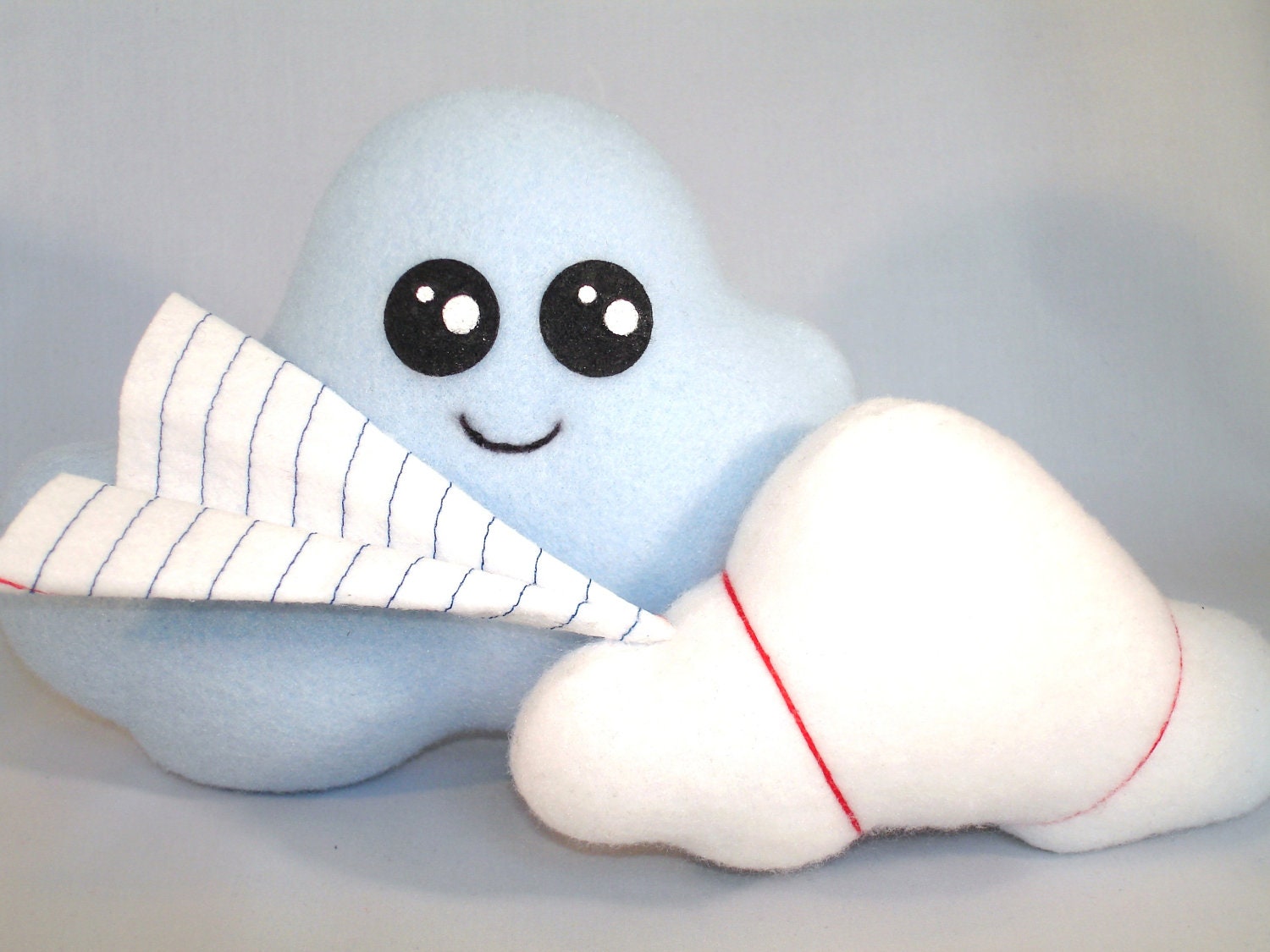 stuffed cloud toy with felt "paper" airplane attached in baby blue fleece