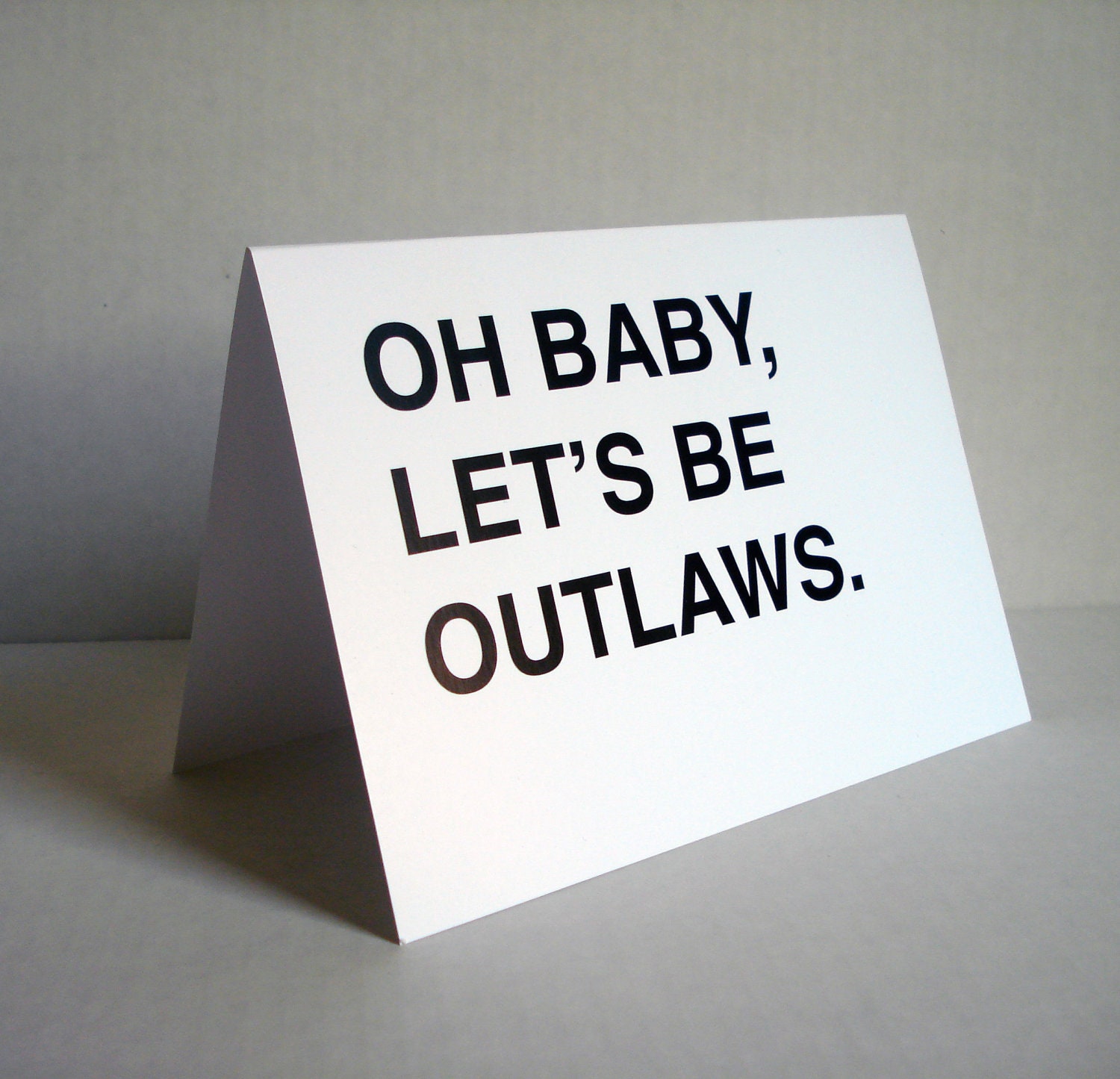 oh baby, let's be outlaws greeting card - black