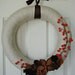 Ivory yarn wrapped wreath with 3 toned brown flowers and orange berries