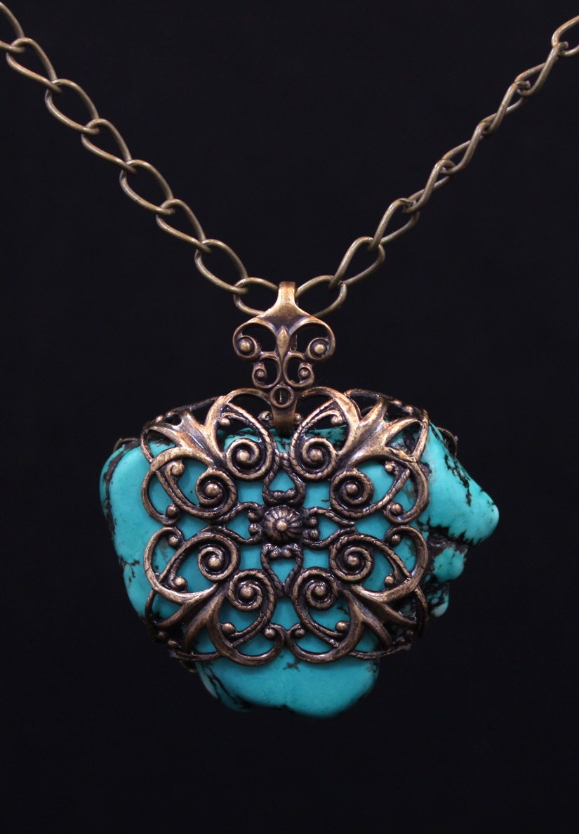 Natural turquoise stone pendant wrapped with antiqued brass filigree.