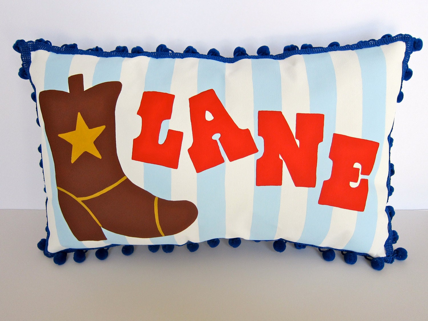 Baby pillow in baby blue stripes with cowboy boot accent. Personalized with name.