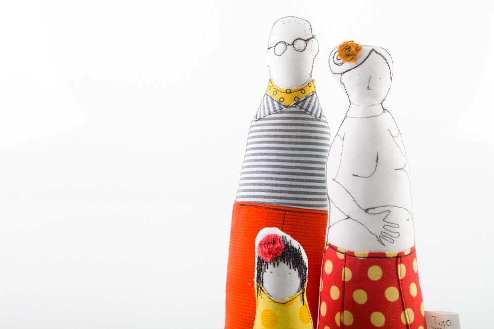 Young family - man in striped shirt scarf and orange corduroy, pregnant woman in red spotted skirt and girl in yellow, handmade fabric dolls